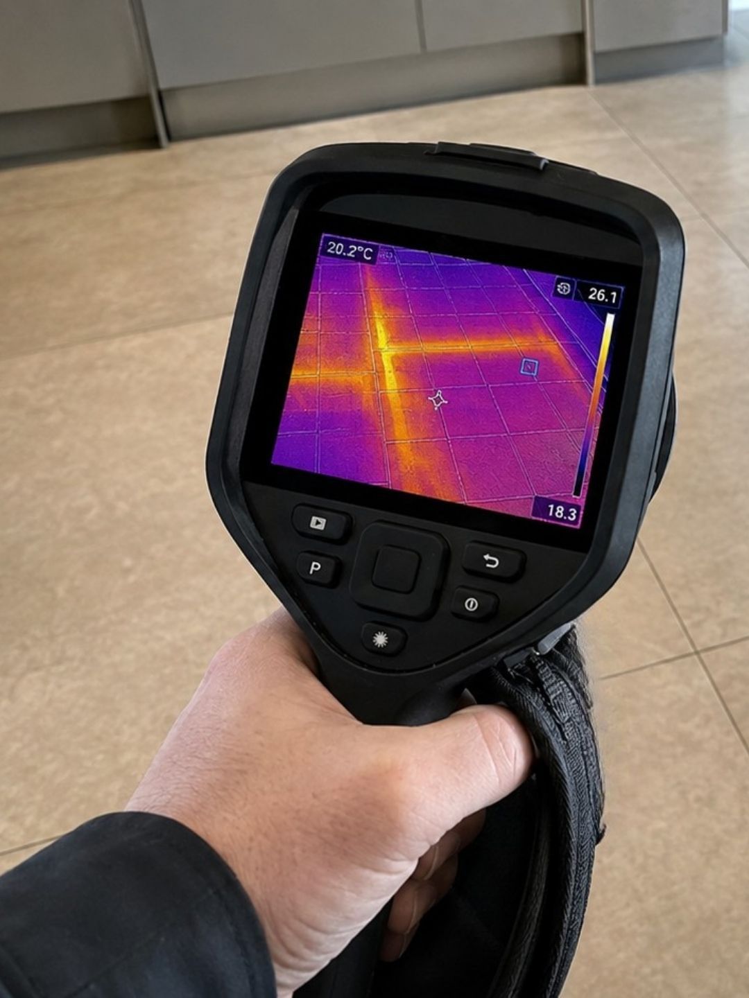 Thermal imaging camera showing temperature patterns beneath a tiled floor.